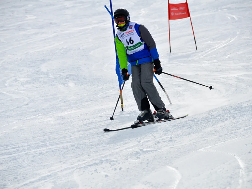 Skifahrer in tiefer Hocke zwischen zwei Toren.